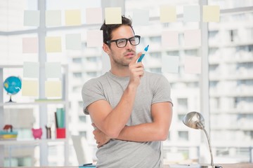 Thoughtful man looking at sticky notes on window