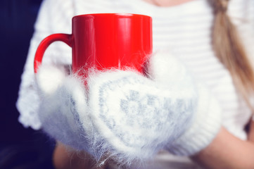 hands in white mittens and red mug tea or coffe