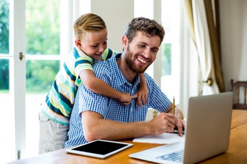 Happy father with son working by technologies at table 