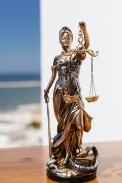 Justice Themis goddess sculpture on bright sky copy space background.