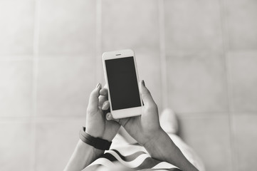 Female holding using a smartphone and shopping box. Top view closeup