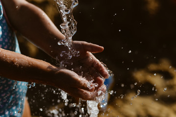 Child hand and water wet sand blurry outdoors background - obrazy, fototapety, plakaty