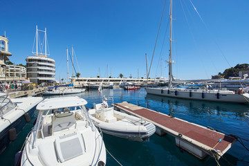 Fototapeta premium Monaco, Monte-Carlo, Monaco Ville, 8 August 2016: Port Hercules, the preparation of the yacht show MYS, sunny day, many yachts and boats, RIVA, Prince's Palace of Monaco, megayachts, Massif of houses