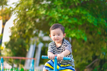 Asian kid riding seesaw board at the playground