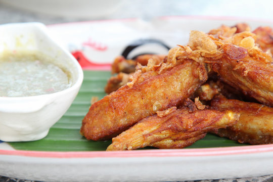 Fried chicken wing with chili sauce in white plate.