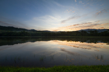 Green grass, lake, mountains and forest during sunrise with dim light, thailand