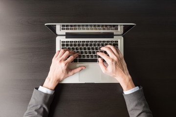 Top view of Businessman using Laptop on the black desk.