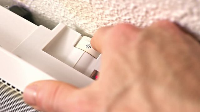 d&eacute;tail main d&rsquo;homme qui allumme un radiateur &eacute;lectrique