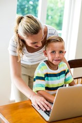 Happy mother and son using laptop at home 