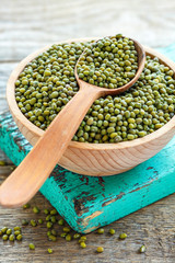 Wooden spoon in a bowl of mung beans.