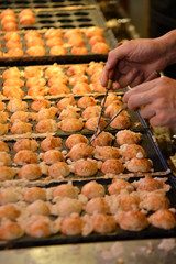 Naklejka premium Takoyaki is a ball-shaped Japanese snack made of a wheat flour-based batter and cooked in a special moulded pan.