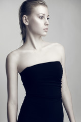 Fashion beauty portrait of beautiful blonde model in black dress with nude makeup.