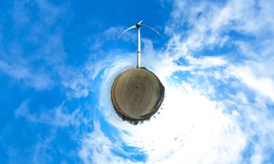 Little planet - spherical view of wind turbine on farm field with blue sky