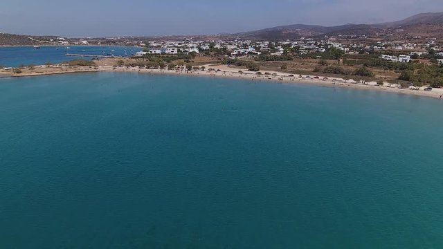 Flying over blue ocean towards beach and village, Greece