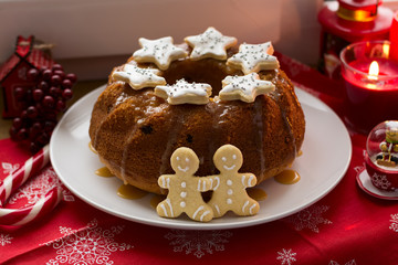 Christmas decoration: cake, gingerbread-men and burning red candles on windowsill