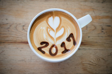 hot coffee with foam milk art 2017 on wooden table