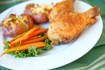 Fried chicken drumsticks with crushed potatoes and roasted carrots