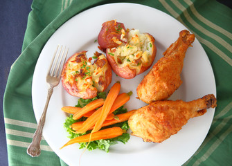 Overhead of fried chicken, carrots and potatoes with striped napkin