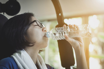Asian woman drinking water after her workout.