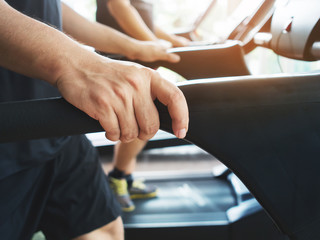 man hands holding on treadmill machine while working out at a gy