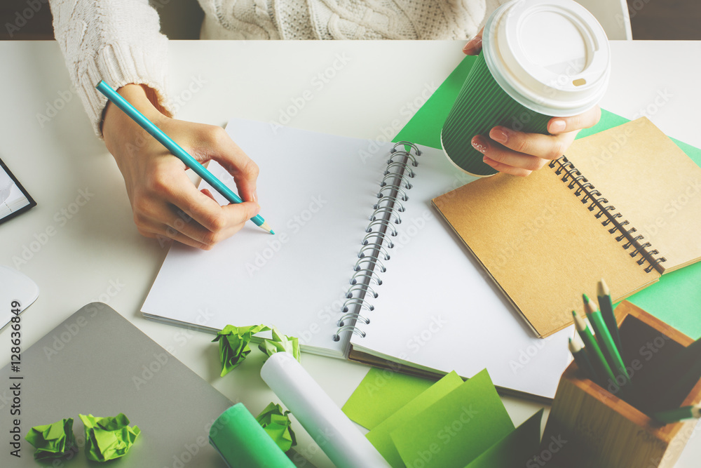 Wall mural Female with coffee writing in notepad