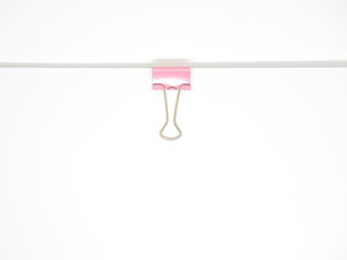 Pink paperclip attached on white paper isolated