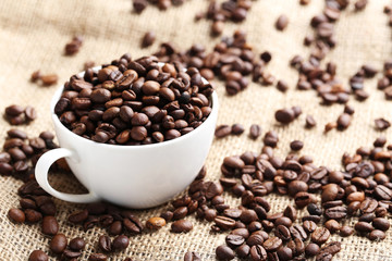 Fototapeta na wymiar Brown roasted coffee beans in cup on sackcloth