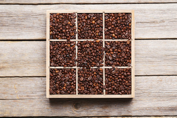 Roasted coffee beans in wooden basket on grey table
