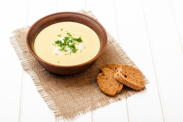 Broccoli cream soup on white wooden table.