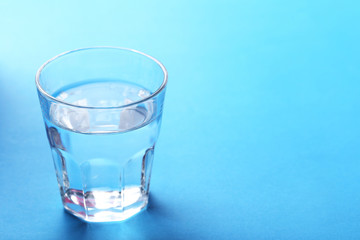 Glass with water on blue background