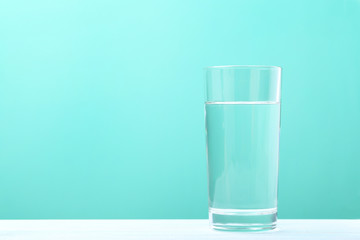 Glass with water on mint background