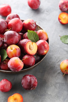Fresh plums on a grey wooden table