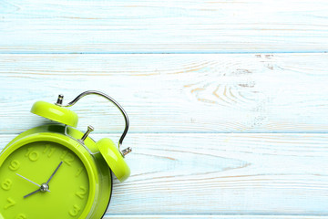 Green alarm clock on a blue wooden table