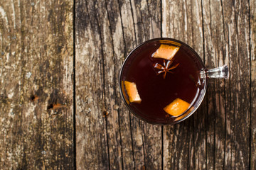 Mulled wine with spices on wooden background. Top view. Space for text.