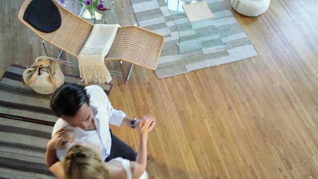 Couple dancing accross floor at home, high angle view