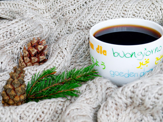 Obraz na płótnie Canvas A cup of hot tea, dressed in knitted warm scarf winter warm knitted sweater or blanket. Still scarf and a cup of tea with Christmas tree. In the winter time. Cozy and soft winter background.