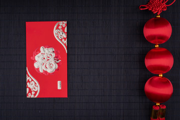 Fototapeta na wymiar chinese knot and red envelope on black bamboo mat