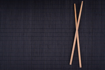 crossed chopsticks on black bamboo mat, overhead, background, flat lay, overhead