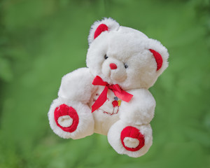 White toy teddy bear on a green background .
