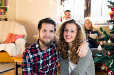 Young friends at decorated Christmas tree celebrating Christmas 