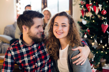 Fototapeta premium Young friends at decorated Christmas tree celebrating Christmas 