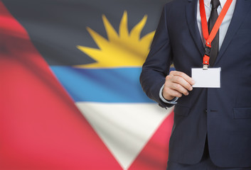 Businessman holding name card badge on a lanyard with a national flag on background - Antigua and...