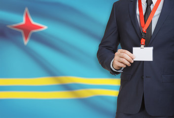 Businessman holding name card badge on a lanyard with a national flag on background - Aruba