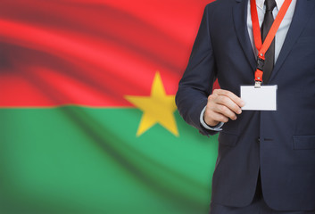 Businessman holding name card badge on a lanyard with a national flag on background - Burkina Faso