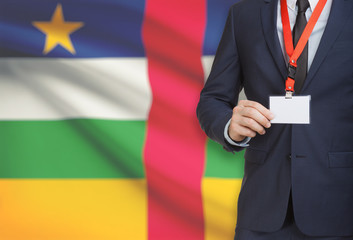 Businessman holding name card badge on a lanyard with a national flag on background - Central...