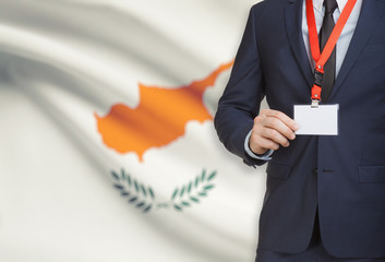 Businessman holding name card badge on a lanyard with a national flag on background - Cyprus