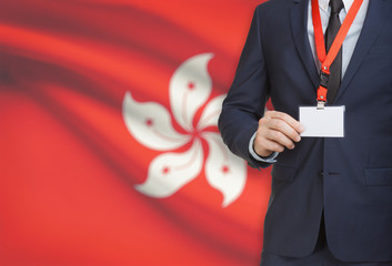Businessman holding name card badge on a lanyard with a national flag on background - Hong Kong