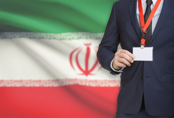 Businessman holding name card badge on a lanyard with a national flag on background - Iran