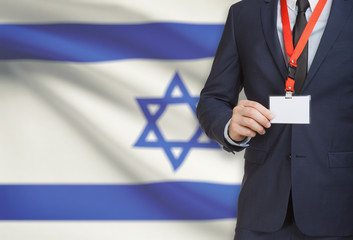 Businessman holding name card badge on a lanyard with a national flag on background - Israel