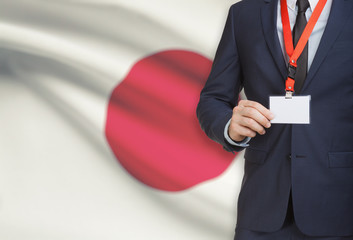 Businessman holding name card badge on a lanyard with a national flag on background - Japan